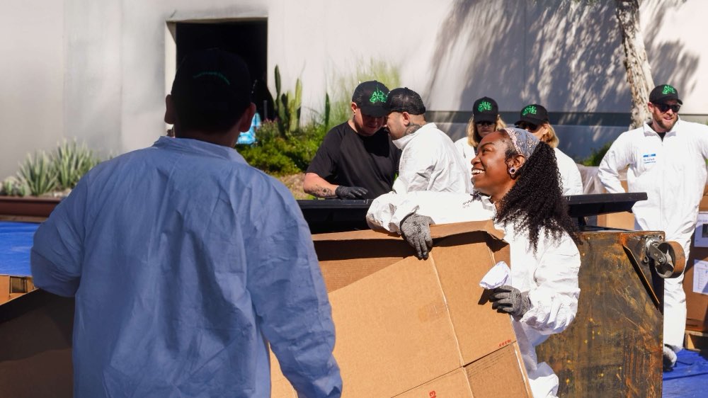 Employees in coveralls sorting waste at the annual Dumpster Dive