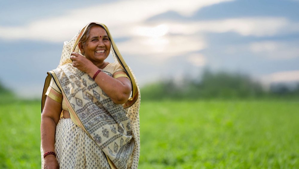 Shakuntla Devi, a farmer with their mint supplier in India, in a green field